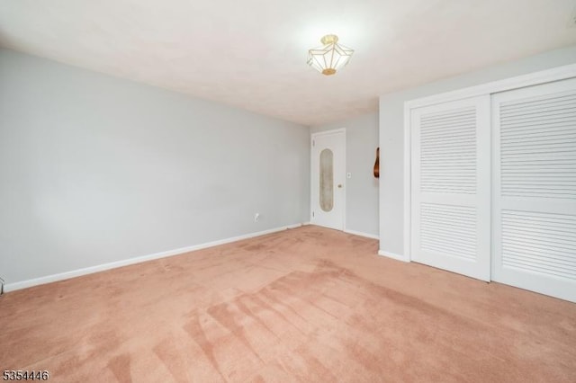 unfurnished bedroom featuring baseboards, a closet, and light carpet