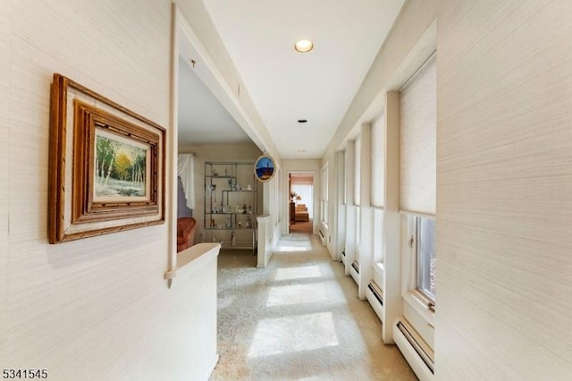 hallway featuring light carpet and baseboard heating