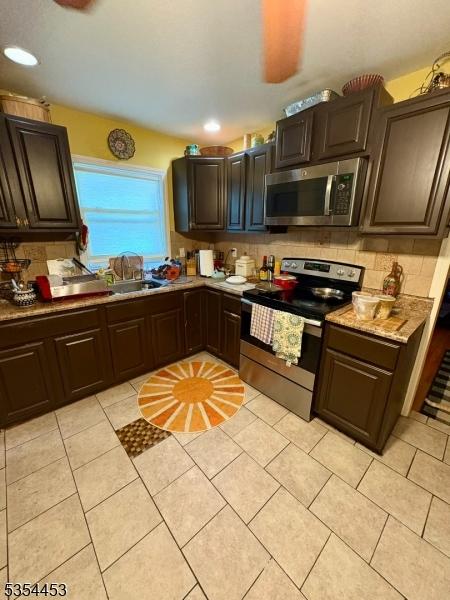 kitchen with stainless steel appliances, tasteful backsplash, a sink, dark brown cabinetry, and recessed lighting