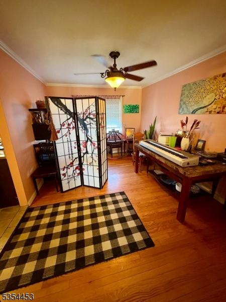 entryway with wood finished floors, crown molding, and a ceiling fan
