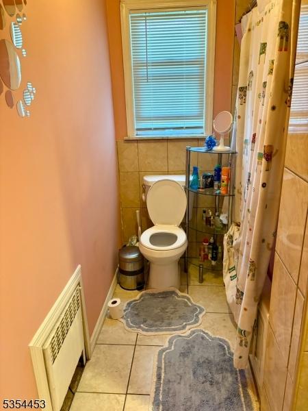 bathroom with tile patterned floors, tile walls, toilet, and a shower with shower curtain