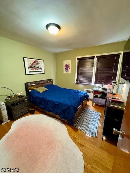 bedroom featuring radiator heating unit and wood finished floors