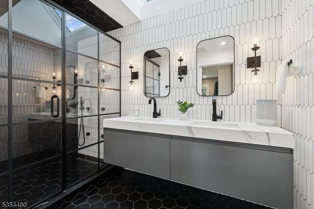 full bath with a skylight, a stall shower, double vanity, and tile walls