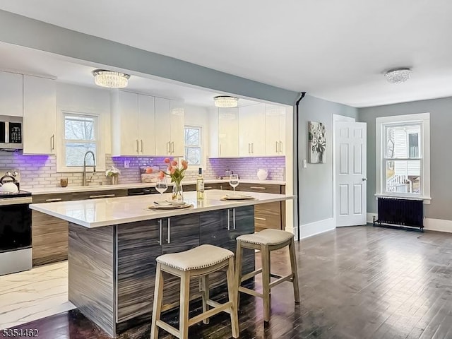 kitchen with light countertops, stainless steel microwave, a breakfast bar area, and range with electric cooktop