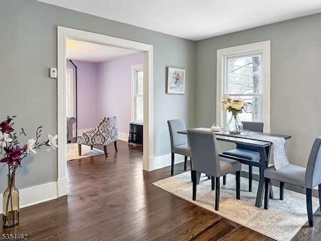 dining area with baseboards and dark wood-type flooring