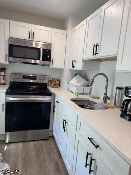 252 Spring St, Newton Town, NJ 07860 - kitchen with stainless steel appliances, a sink, white cabinetry, and dark wood-style floors