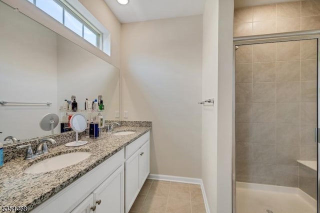 full bath featuring a sink, baseboards, a stall shower, and double vanity