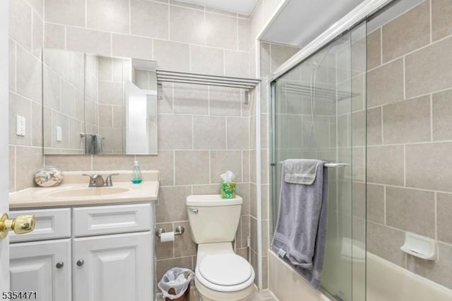 full bath featuring vanity, toilet, tile walls, enclosed tub / shower combo, and backsplash