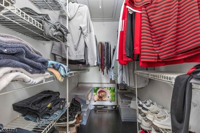 walk in closet with attic access and wood finished floors
