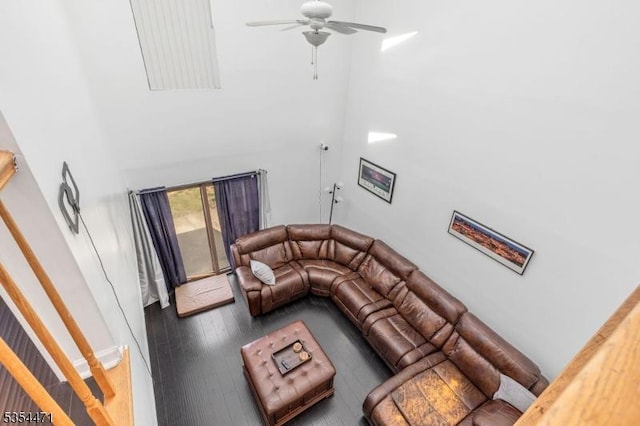 living area with wood finished floors, baseboards, ceiling fan, and a high ceiling