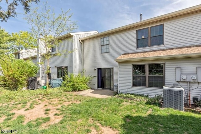 rear view of property featuring a lawn and central air condition unit