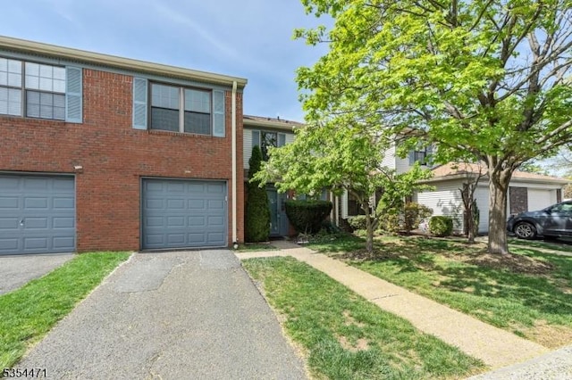 multi unit property featuring a garage, a front yard, driveway, and brick siding