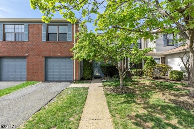 multi unit property with brick siding, driveway, and a garage