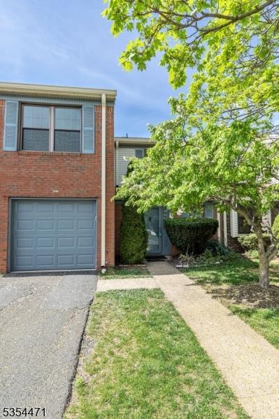 view of front of property with brick siding, an attached garage, and driveway