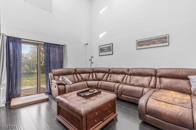 living area featuring dark wood-style floors and a towering ceiling