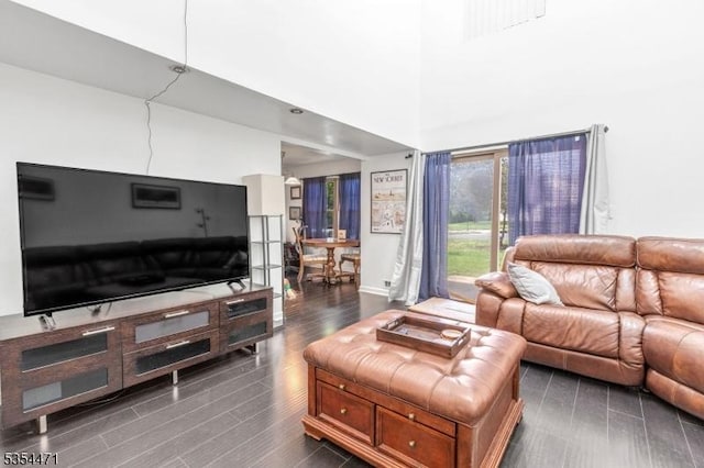living room featuring dark wood-style flooring, a high ceiling, and baseboards