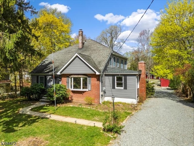 bungalow-style house with brick siding, a front lawn, and a chimney