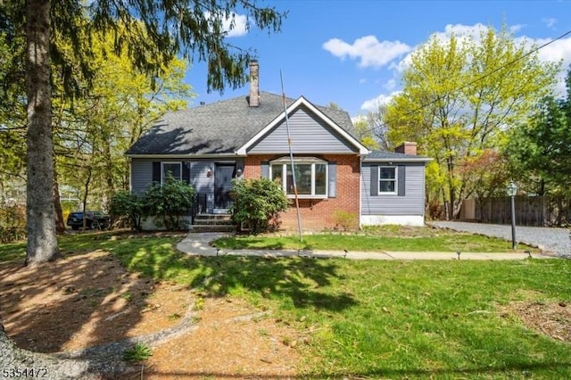 bungalow with fence, a chimney, brick siding, and a front yard