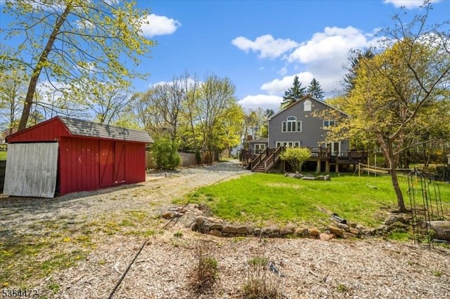 view of yard with stairway, an outdoor structure, a wooden deck, and a shed