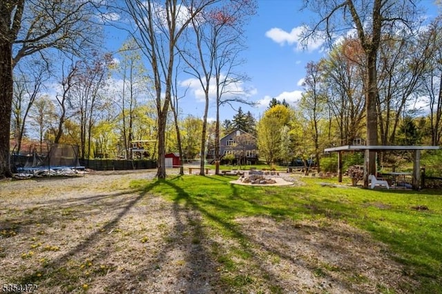 view of yard with a storage shed, a trampoline, an outbuilding, and a fire pit