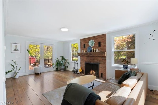 living area featuring baseboards, a brick fireplace, hardwood / wood-style flooring, and french doors