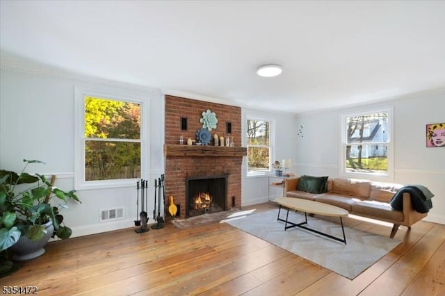 living room with visible vents, wood-type flooring, baseboards, and a fireplace