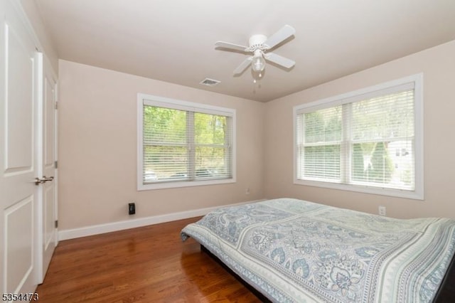 bedroom with baseboards, visible vents, multiple windows, and wood finished floors