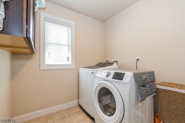 washroom featuring light tile patterned floors, baseboards, cabinet space, and washing machine and clothes dryer