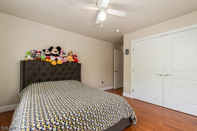 bedroom with baseboards, a ceiling fan, wood finished floors, and a closet