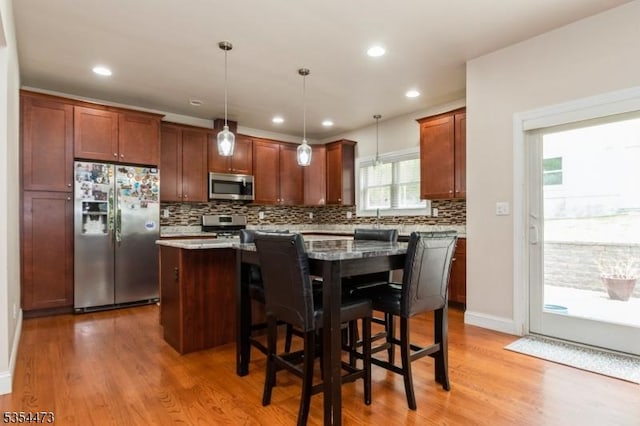 kitchen with a kitchen island, stainless steel appliances, decorative backsplash, and wood finished floors