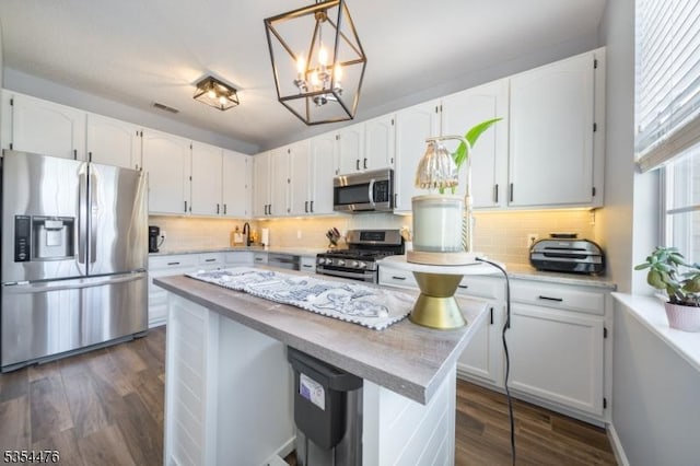 kitchen with white cabinetry, appliances with stainless steel finishes, a chandelier, and tasteful backsplash