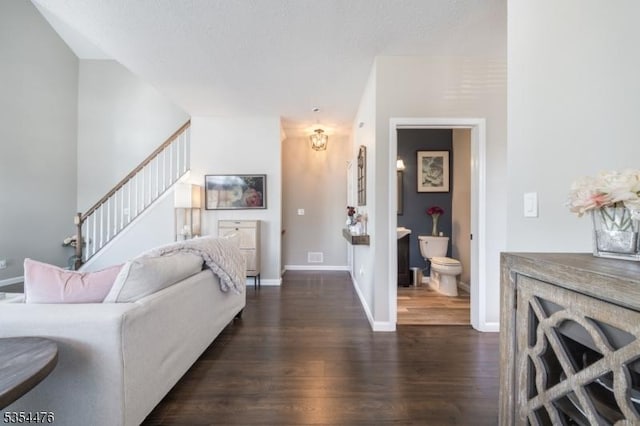 living area with baseboards, a notable chandelier, dark wood finished floors, and stairs