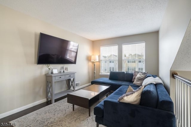 living area with visible vents, baseboards, a textured ceiling, and wood finished floors