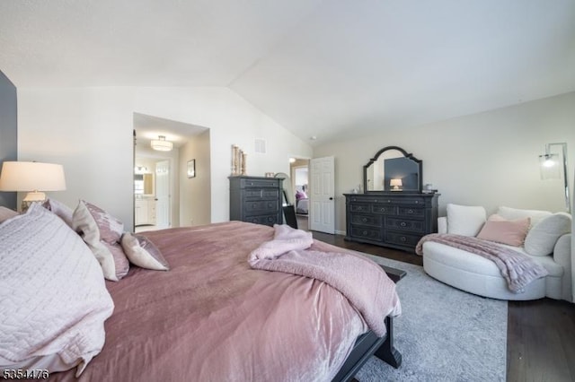 bedroom featuring visible vents, wood finished floors, lofted ceiling, and ensuite bath
