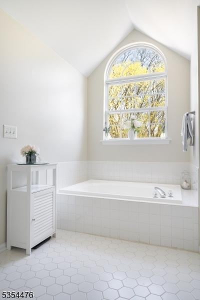 full bathroom with tile patterned flooring, lofted ceiling, and a garden tub
