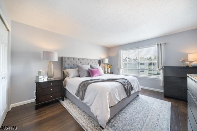 bedroom featuring baseboards, a textured ceiling, and dark wood-style flooring