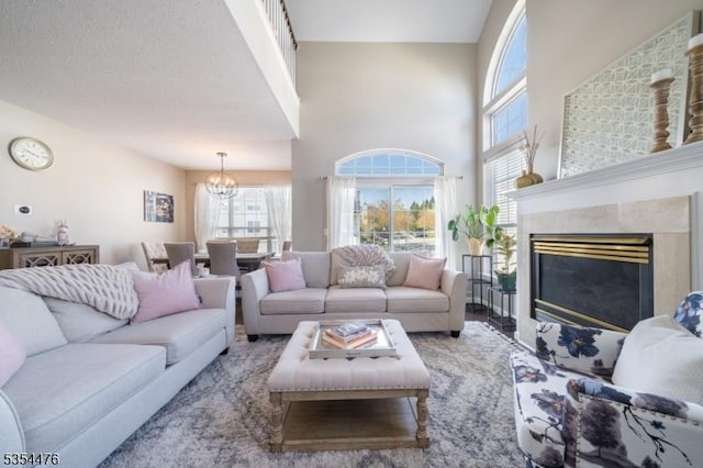 living room featuring an inviting chandelier, a towering ceiling, plenty of natural light, and a fireplace