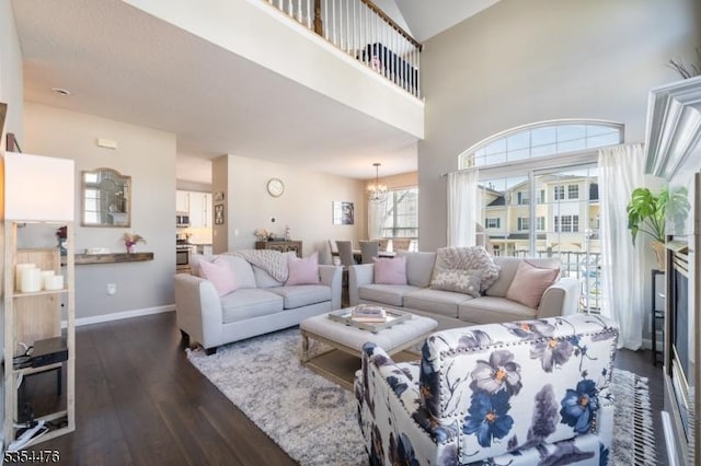 living room featuring an inviting chandelier, baseboards, and dark wood-style floors