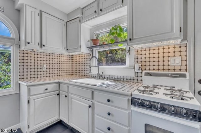 kitchen with a sink, white cabinetry, white gas stove, and light countertops