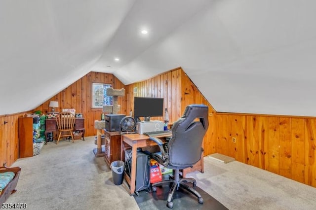 carpeted office space featuring wooden walls and vaulted ceiling