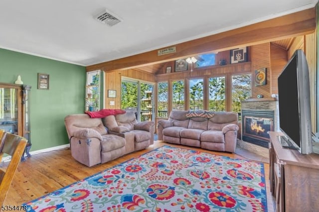 living room featuring visible vents, ornamental molding, wooden walls, and a healthy amount of sunlight