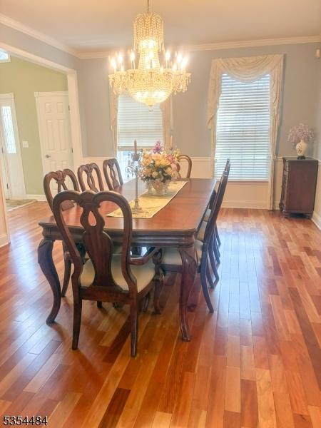 dining area with crown molding, baseboards, wood finished floors, and a chandelier