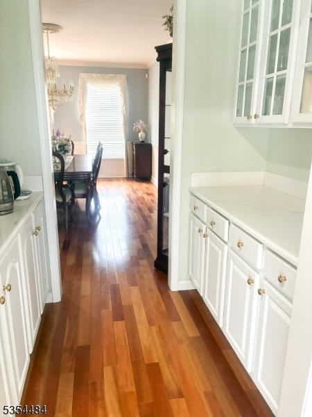 hall with dark wood-type flooring and a notable chandelier
