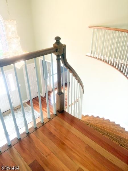 stairs featuring a notable chandelier and wood finished floors