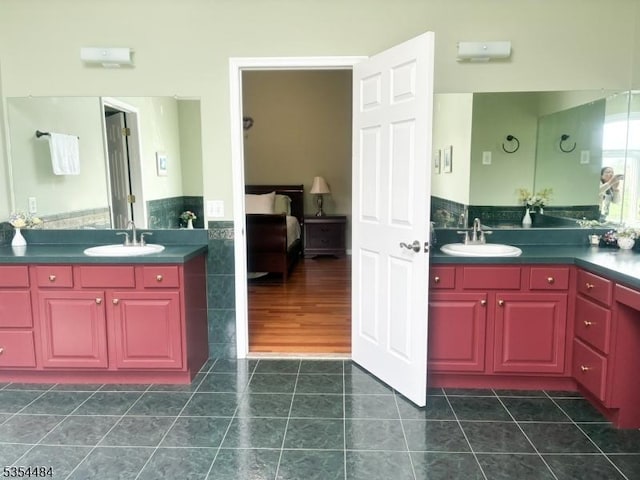 full bath with a sink, a wainscoted wall, tile patterned flooring, and ensuite bath