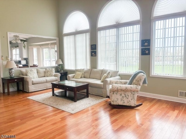 living room with baseboards, ceiling fan, wood finished floors, and visible vents