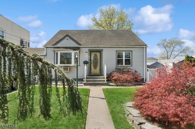 bungalow with roof with shingles and a front yard