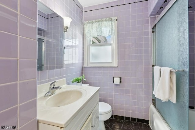 bathroom featuring enclosed tub / shower combo, toilet, tile walls, and vanity