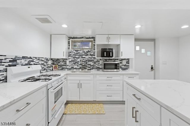 kitchen featuring a sink, decorative backsplash, stainless steel microwave, and white range with gas stovetop