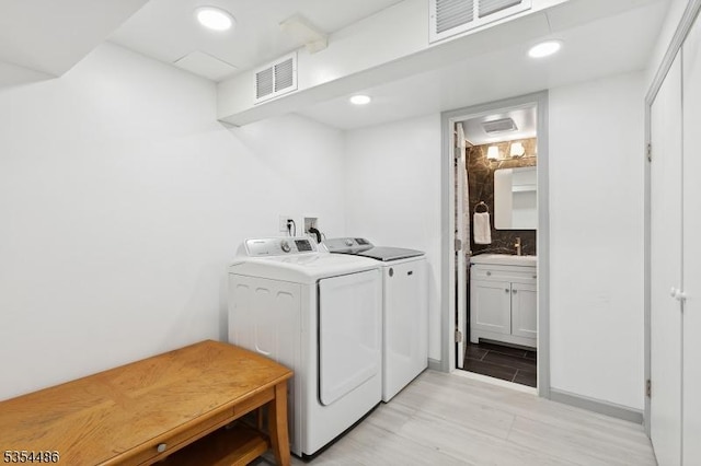 clothes washing area featuring recessed lighting, visible vents, washing machine and dryer, and a sink